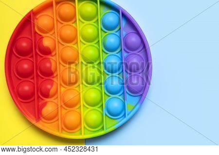Popular Silicone Multi-colored Anti-stress Toy Pop It On Yellow Blue Background Flat Lay Top View. T