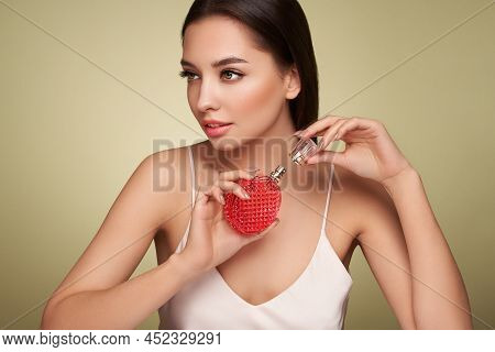 Young Beautiful Woman With A Bottle Of Perfume. Model With Healthy Skin, Close Up Portrait. Cosmetol