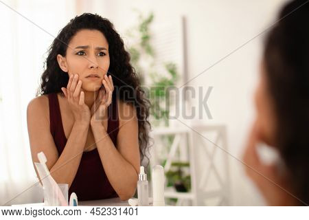Unhappy Millennial Woman Looking At Her Reflection In Mirror, Checking First Wrinkles At Bathroom, C