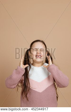 Portrait Of Young Angry Girl With Long Hair In Pink, White Sweater Standing With Closed Eyes, Clench
