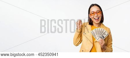 Microcredit And Money Concept. Stylish Asian Young Woman In Sunglasses, Laughing Happy, Holding Doll