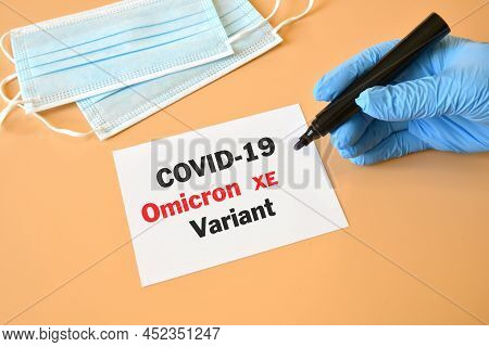 Covid-19 New Omicron Xe. Hand Of The Doctor In Blue Glove With Marker And Writing 