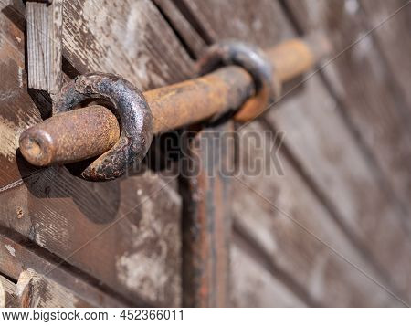 Old Rusty Metal Deadbolt On A Wooden Door. Close-up