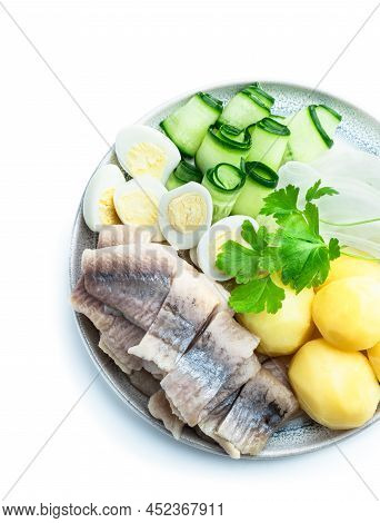 Salted  Herring With Boiled Potatoes And Quial Eggs On A White Plate Isolated On White