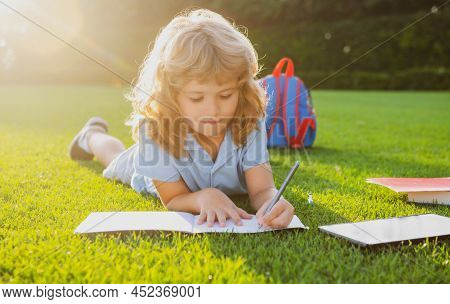 Cute Childr Boy With Books With Pencil Writing On Notebook Outdoors. Summer Camp. Kids Learning And 