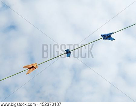 Clothespins Hanging On A Washing Line Under Tropical Cloudy Sky. Clothes Pins On A Clothes Line Rope