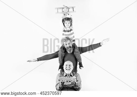 Three Different Generations Ages Grandfather Father And Child Son Playing With Toy Plane In Studio. 