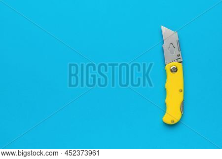 Unfolded Folding Knife For Paper And Cardboard On A Blue Background. A Place For Your Text. Minimali