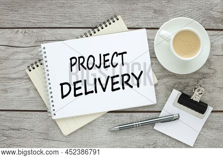 Project Delivery . Two Notepads On A Wooden Table.text On Notepad Page. Near Coffee.