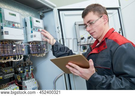 Electrician inspectinf fuse box circuit with tablet computor