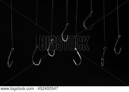 A Fishing Hooks Hanging On A Fishing Line On A Black Background. Concept