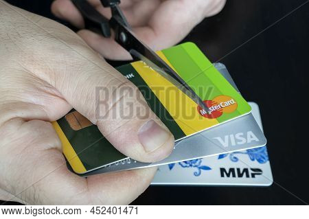 April 2, 2022. Barnaul. Russia: A Man Cuts Bank Credit Cards Of The Type And Mastercard With Scissor