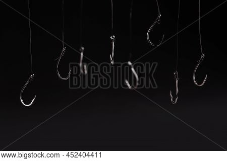 A Fishing Hooks Hanging On A Fishing Line On A Black Background. Concept
