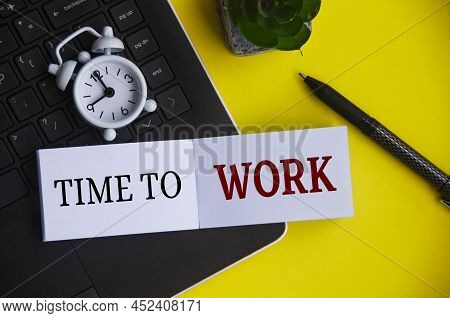 Time To Work Text On Notepad With Alarm Clock And Laptop Background.