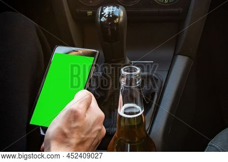 Man Drinking Alcohol While Driving In His Car And Looks In Smartphone.