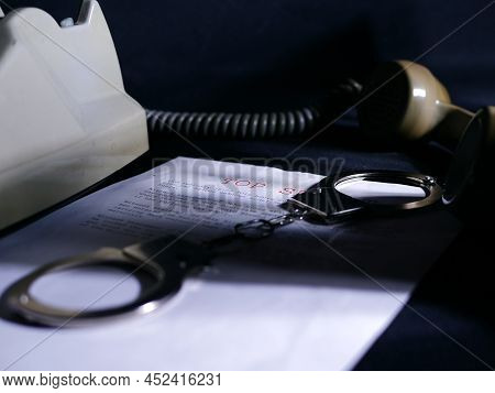 Handcuffs On Top Secret Document In Dark Room