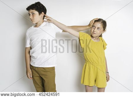 Portrait Of Cute Girl And Boy On Studio White Background Conflit Each Other