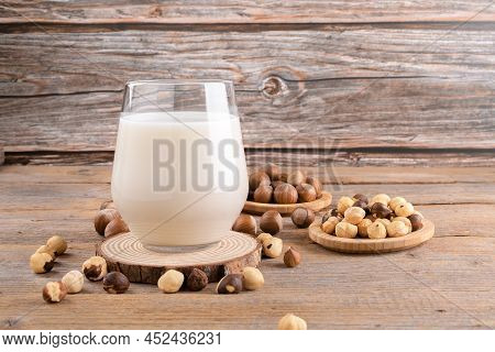 Vegan Non Diary Hazelnut Milk In Glass With Whole Hazelnuts On A Linen Napkin On A Rustic Wooden Bac