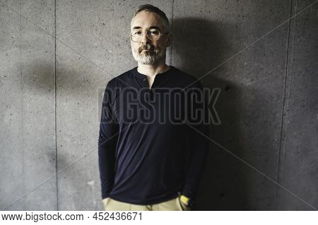 Nice Joyful Mature Man At Home Appartement With Grey Beard In Front Of Concreate Wall