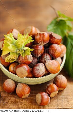 Hazelnuts Close-up In A Green Cup On A Wooden Table. Whole Nuts With Green Leaves. Harvest Of Hazeln