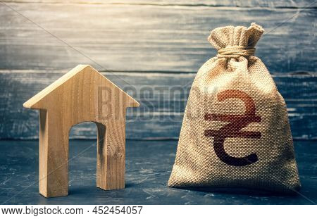 Wooden House And A Ukrainian Hryvnia Money Bag. Home Purchase, Investment In Real Estate Constructio