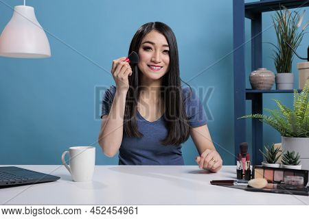 Attractive Videoblogger Doing Makeup In Front Of Camera Using Cosmetic Brush While Recording Online 