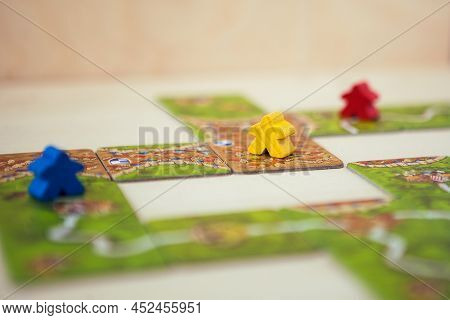 Petrozavodsk, Russia, April 2022: Carcassonne Board Game, Game Cards And Colored Chips On Wooden Tab