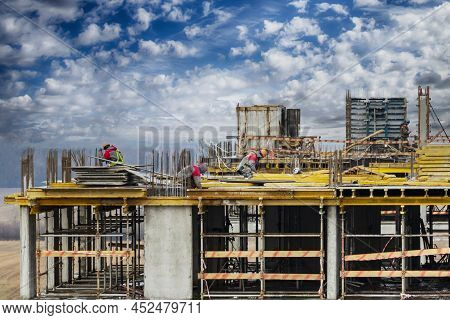 Monolithic Frame Construction Of The Building. Workers Working At The Construction Site At Home. The