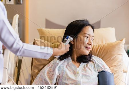 Nurse Checking Patient's Temperature In The Ear With Tympanic Thermometer In Hospital Ward