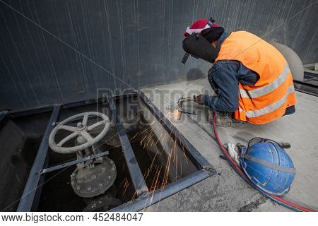 An Asian Man Welding A Metal Grate, Arc Welding Process With Sparks. Long Exposure. Focus On Sparkli