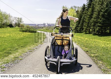 Beautiful Young Family With Baby In Jogging Stroller Running Outside In Summer Season