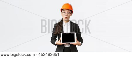 Impressed Asian Female Construction Engineer, Businesswoman In Safety Helmet And Suit Showing Chart,