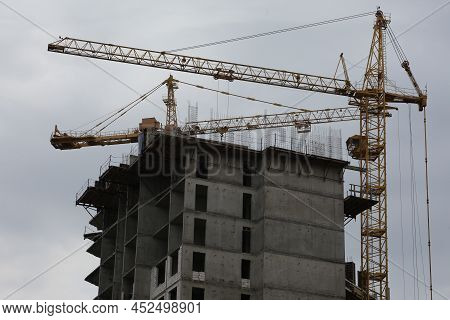 Construction Yellow Crane Builds A Tall Multi-apartment Residential Building From White Bricks And C