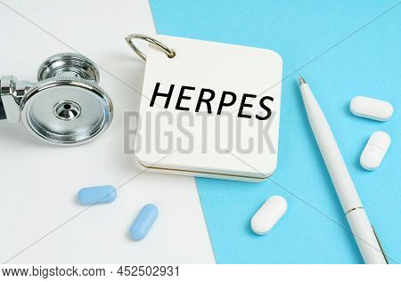 Medical Concept. On A White And Blue Surface Are Pills, A Stethoscope, A Pen And A Notepad With The 