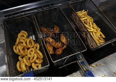 Deep Fried Snack Foods In A Fat Frying Basket, French Fries, Onion Rings And Wings Etc