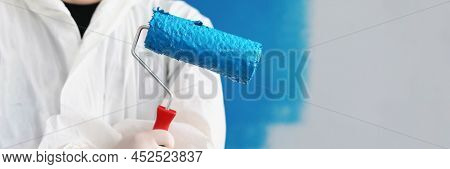 Close-up Of Painter Man Hand Holding Roller Tool For Painting Walls, Blue Colour On Equipment, Worke