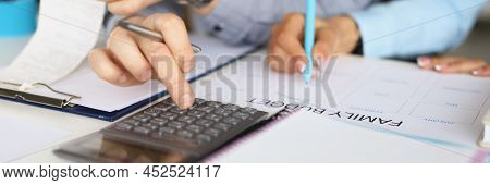 Close-up Of Couple Planning Family Budget For Month. Man Counting On Calculator, Woman Write Down On