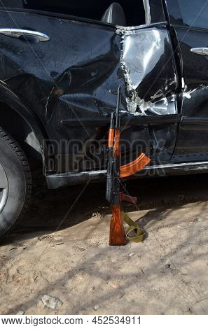 AKM(Avtomat Kalashnikova) version of Kalashnikov assault rifle and car wreck. April 7, 2022. Kiev Region, Ukraine