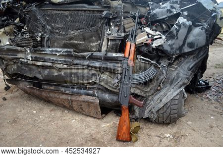 AKM(Avtomat Kalashnikova) version of Kalashnikov assault rifle and car wreck. April 7, 2022. Kiev Region, Ukraine