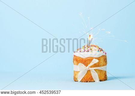 Easter Cake With Baw And Sparkler On Blue Background, Easter Food. Minimal Concept