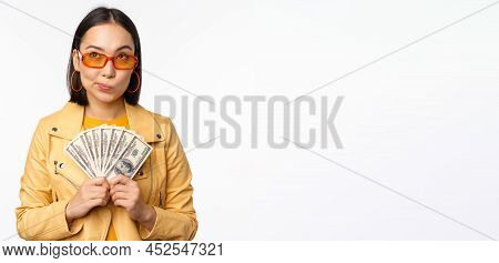 Microcredit And Money Concept. Stylish Asian Young Woman In Sunglasses, Laughing Happy, Holding Doll