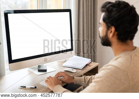 Back View Of Positive Hindi Man In Smart Casual Clothes Using Computer While Sitting At The Desk In 