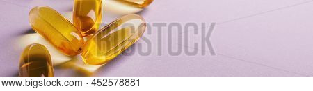 Fish Oil. Yellow Softgels Or Capsules Lie On A Pink Surface. Vitamins And A Healthy Lifestyle. Banne