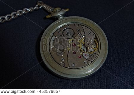 The Interior (mechanism - Werk ) Of An Antique Pocket Watch On A Black Background.