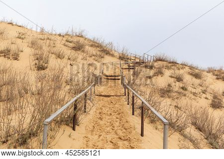 The Staircase Rises To A Sandy Dune. Climbing To The Top In The Desert. Sarykum Dune. Dagestan, Russ