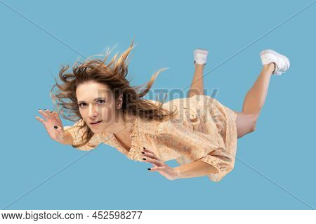Beautiful Young Woman Levitating In Mid-air, Falling Down And Her Hair Messed Up Soaring From Wind, 