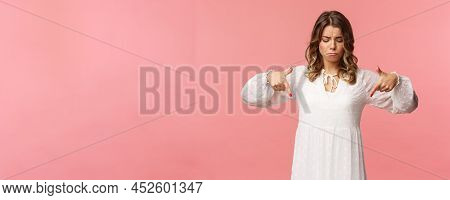Gloomy, Jealous And Upset Cute Blond European Woman In White Trendy Spring Dress, Sulking As Pointin