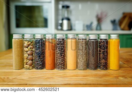 Different Spices In Glass Flasks For Spices On The Table In Home Kitchen With Copy Space.
