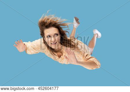 Beautiful Young Woman Levitating In Mid-air, Falling Down And Her Hair Messed Up Soaring From Wind, 