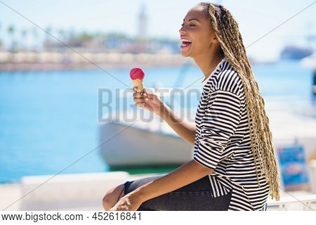 Beautiful Young Black Woman Eating A Strawberry Ice Cream While Enjoying The View Of The Seaport.